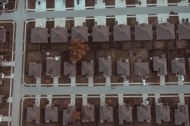 Top view image of a suburban neighborhood with houses, roads, and driveways.