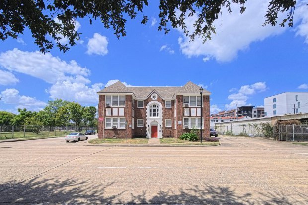 Front view of a vintage brick building under a clear blue sky in Houston, Texas.